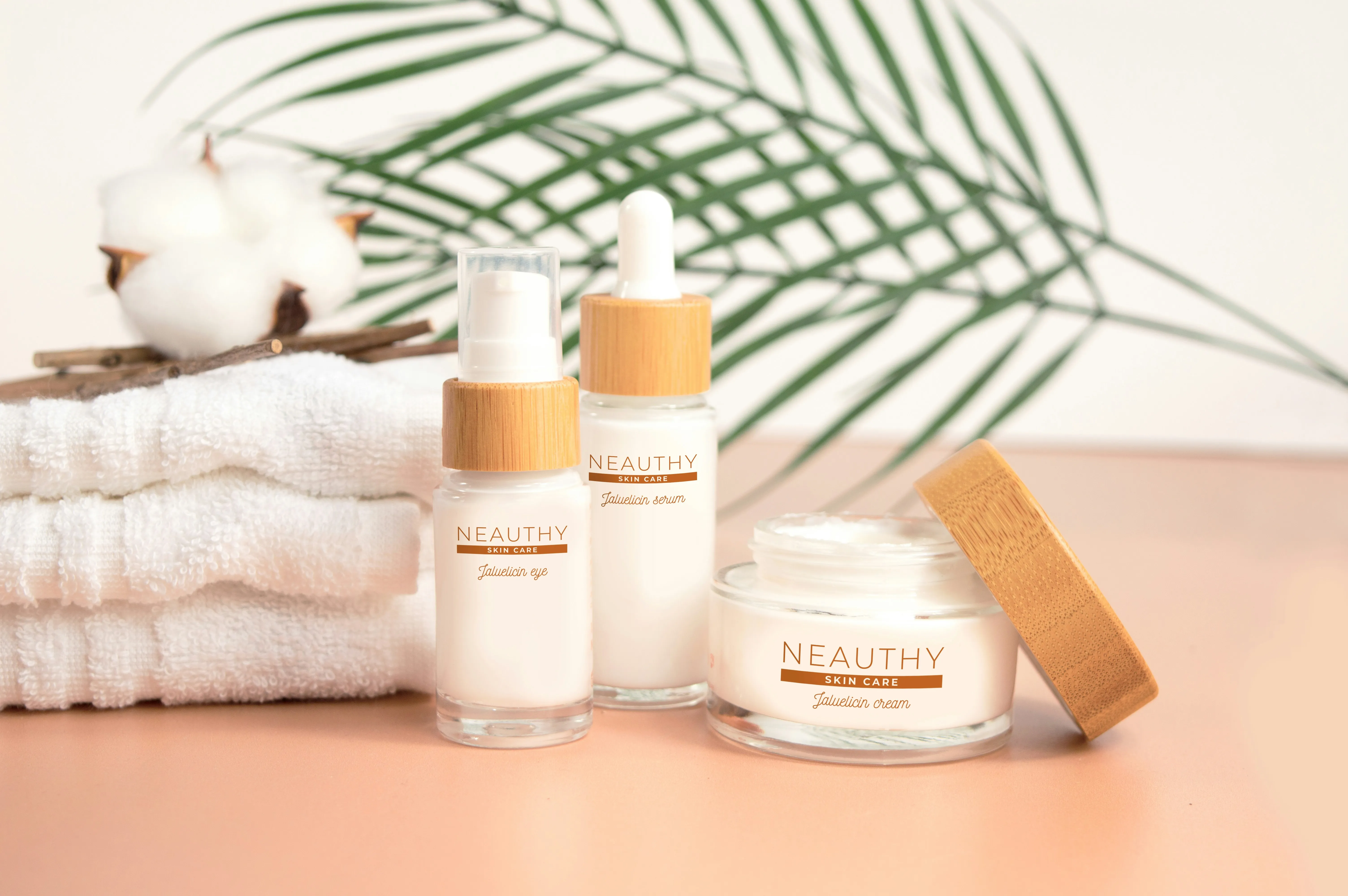 Three Neuthy skincare products, a cleanser with a pump bottle, a serum in a dropper bottle and a moisturizer in a jar wit the lid off..